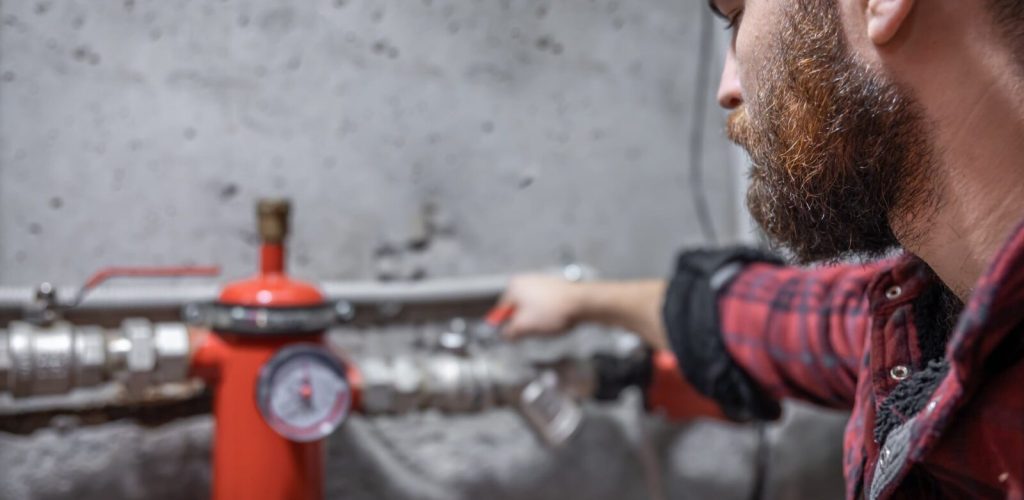 man-looks-faucet-pipes-valve-pressure-meter